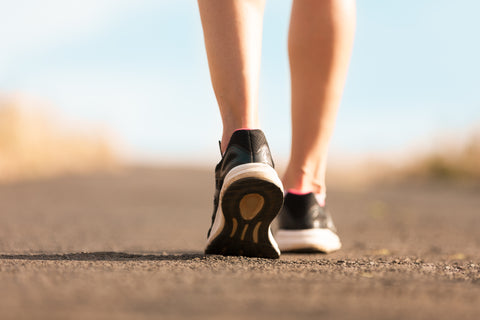 Mujer caminando por una carretera con zapatillas negras