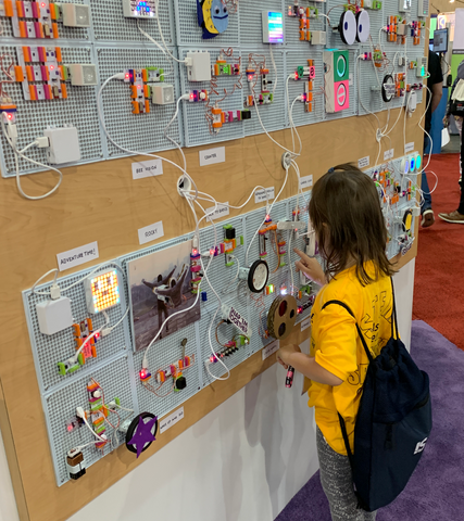 Little girl playing with littleBits invention on a tradeshow booth wall.