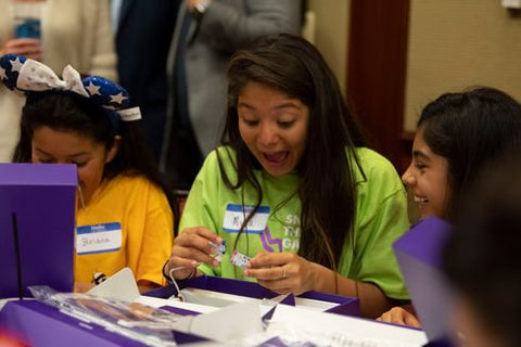 Girls laughing while connecting littleBits together.