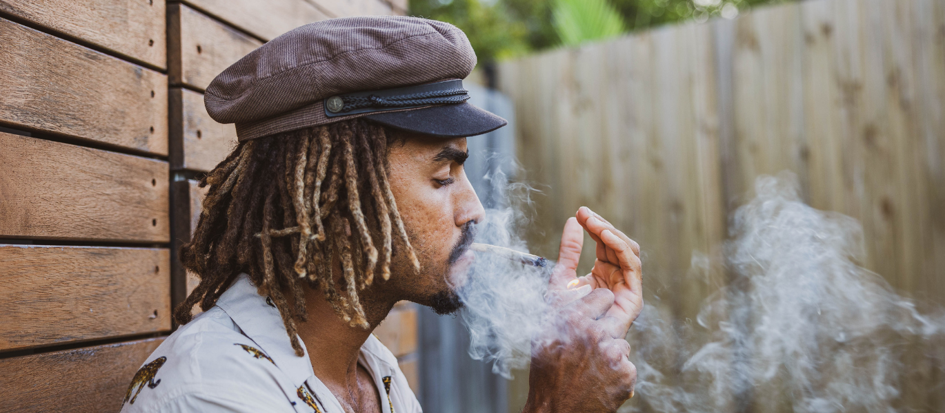 Man smoking cannabis joint and exhaling smoke