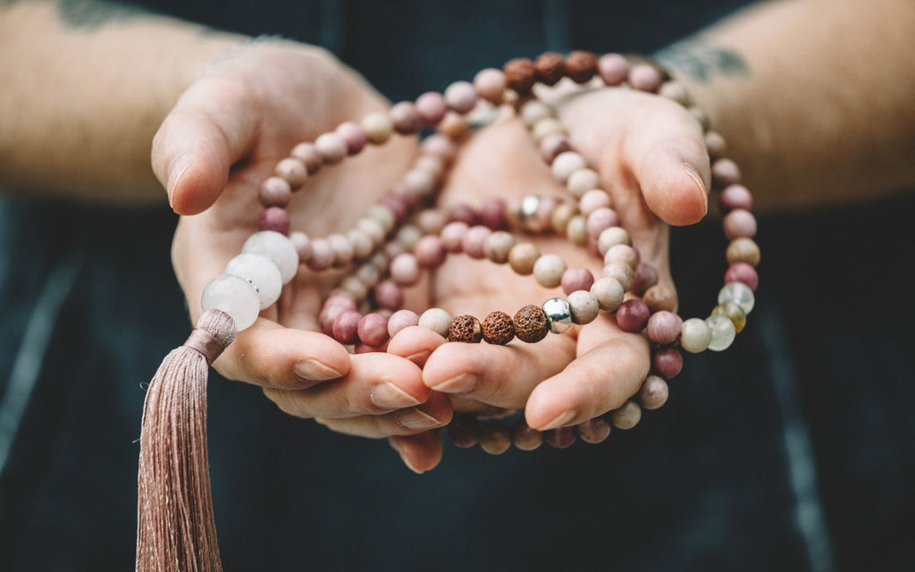 Hand holding a Mala beads necklace with 108 beads