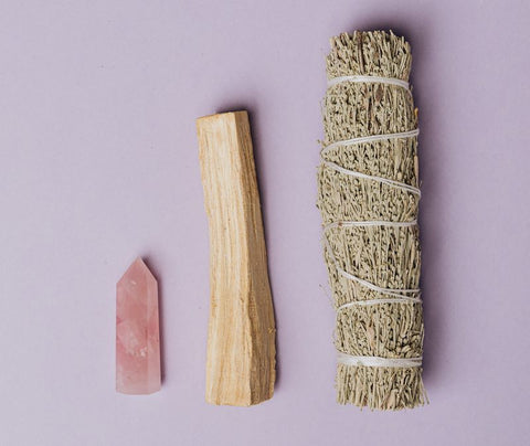 photo of sage and palo santo beside a rose quartz crystal