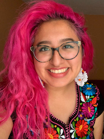 ruby smiling, with long pink hair wearing a traditional huipil