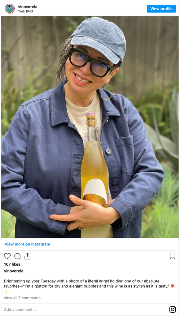 Photo of a woman in a hat holding a bottle of wine