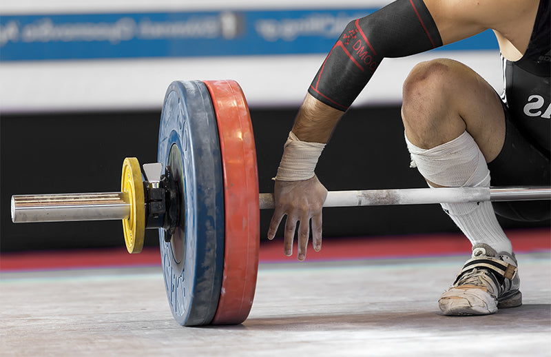 An Olympic bodybuilder wearing DMoose compression elbow sleeve and is ready to lift heavy weight