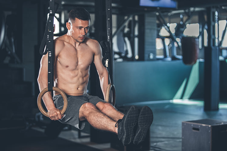 Man, acrobat and gymnastics upside down on rings in fitness for practice,  training or workout at gym. Professional male gymnast hanging on ring  circles for athletics, acrobatics or strength exercise Stock Photo