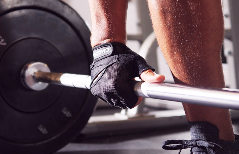 A body builder wearing DMoose weightlifting gloves and trying to lift a heavy weight