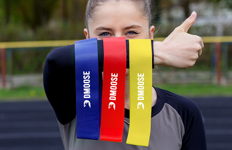 A girl showing Dmoose resistance loop bands doing thumbs up