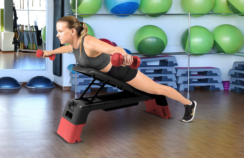 A woman holding dumbbells in her hands while opening hands at 180° and lying on DMoose aerobic deck