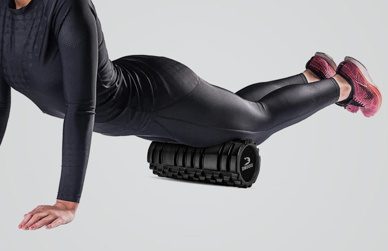 A woman placing DMoose foam roller under her thighs while lying in a push-up position