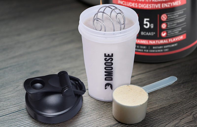 Close view of Dmoose shaker bottle, a spoon full with protein