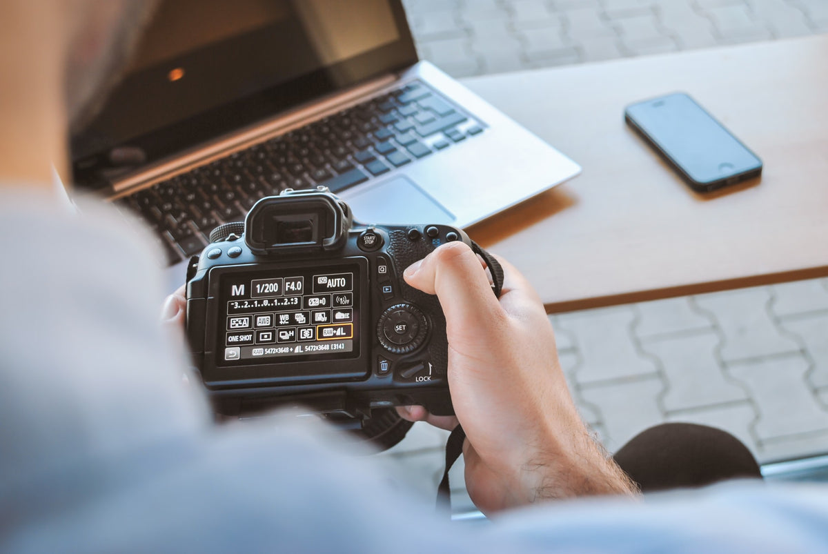  A man working with a camera, laptop, and phone