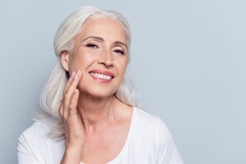 older woman with white hair touching her face 