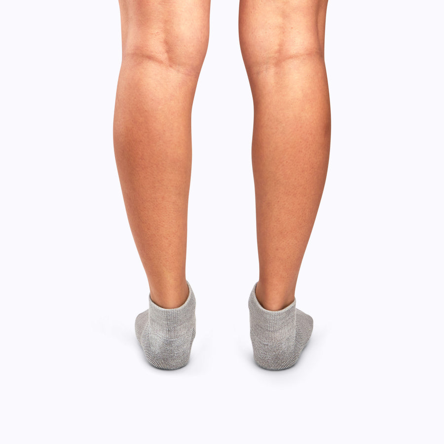 Back view of a pair of legs wearing ankle compression socks in heather grey