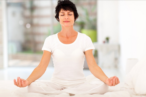 Woman dressed in white, seated and meditating