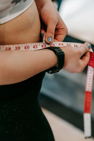 Woman measuring her stomach with a measuring tape