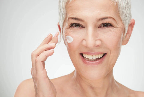 Mature woman applying moisturizing cream to face