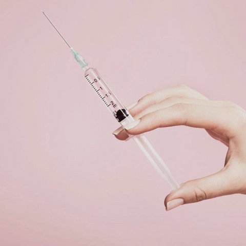 hand holding a needle with pink background