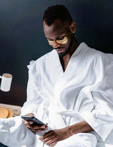 Man using under-eye masks while using cell phone