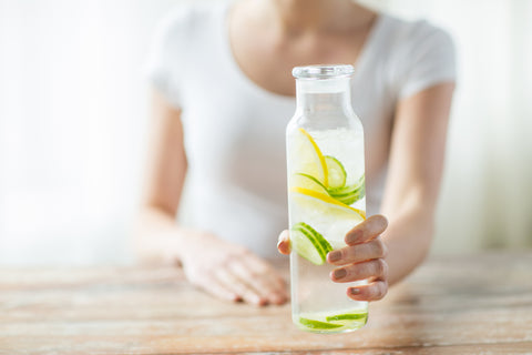 Woman holding bottle of water with lemon and cucumber slices inside