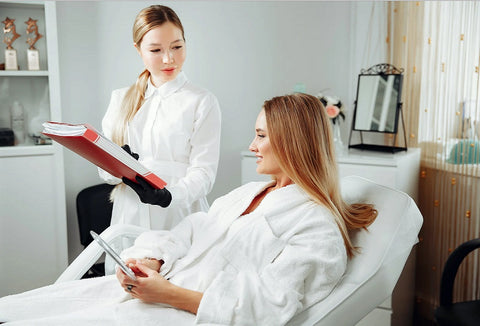 Woman in white robe gets skincare advice from dermatologist