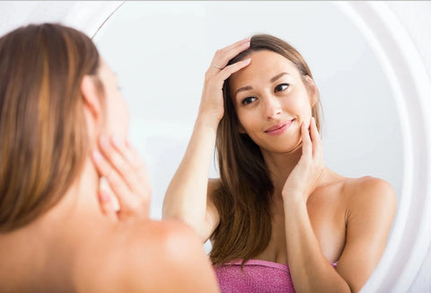 Beautiful Asian American woman examining herself in the mirror