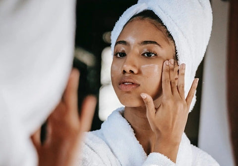 Black woman applying cream to face