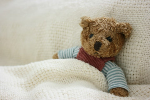 A cute teddy bear lying down in bed