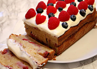 A rectangular shaped sponge cake with strawberries and berries on the top