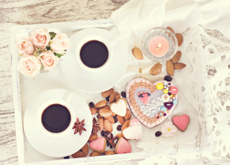 Simple yet elegant breakfast in bed with coffees and heart shaped biscuits