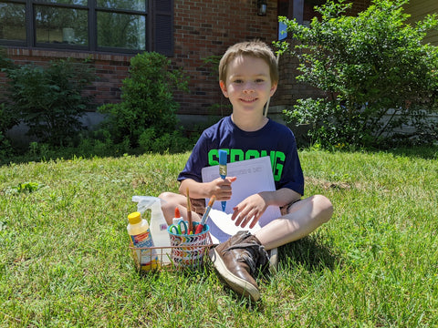 A child posing with craft supplies to make a DIY father's day monster printable card.
