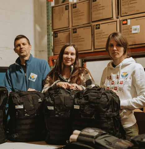 A team of three volunteers from Sunflower of Peace, an organization that supplies life-saving medical supplies to Ukraine, are standing with three of their backpacks.