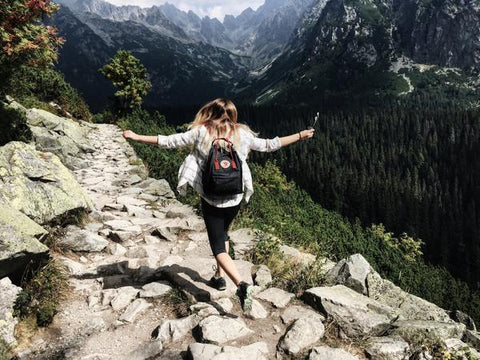 5 Post Corona Virus Ways to "Travel" Your Hometown - A girl hiking through a rocky trail with a black backpack on her back