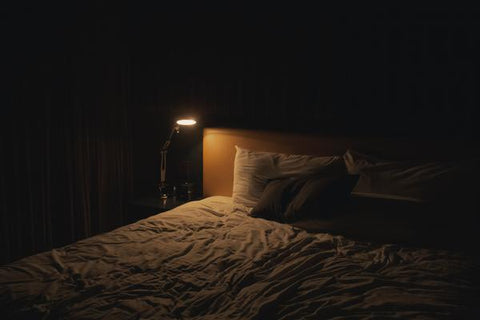 How to Prevent and Combat a Bed Bug Infestation - an empty bed with a dim light on the corner