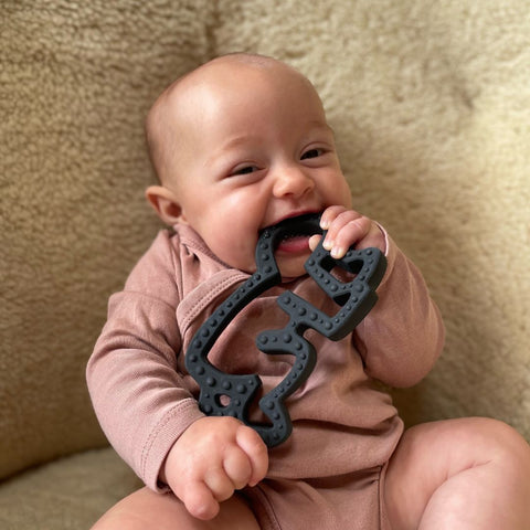 a little baby chewing on the keith haring baby teether by etta loves