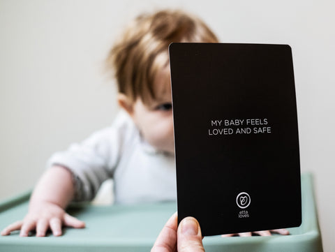 a baby looking at a flashcard with a positive affirmation being read