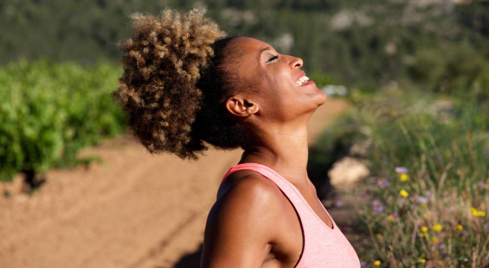 Young woman smiling outdoors under the sunny skies