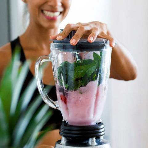 Woman preparing a healthy smoothie on a blender