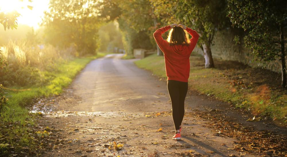 Woman stretching arms before going on a morning walk outdoors during a sunrise
