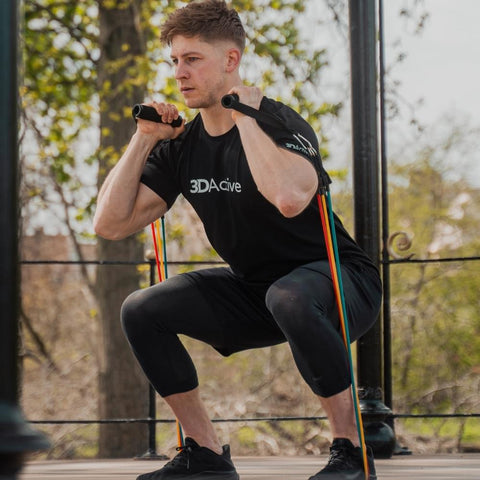 Man doing a squat with resistance bands with handles outdoors