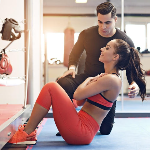 Woman exercising at the gym while personal trainer offers guidance