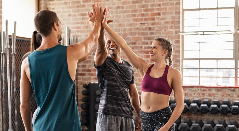 Three young fit people high-fiving. CrossFit workout