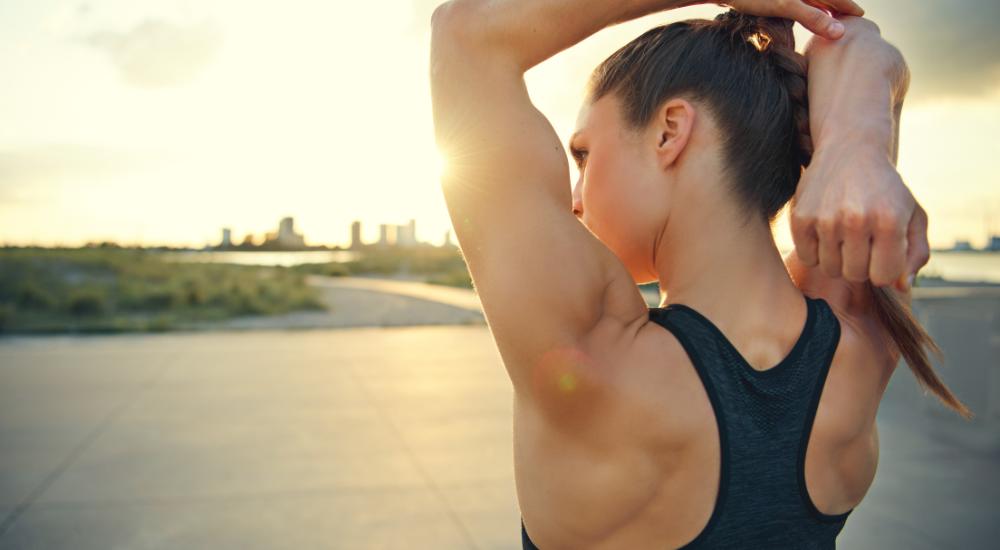 Fit woman stretching arms before going for a jog outdoors