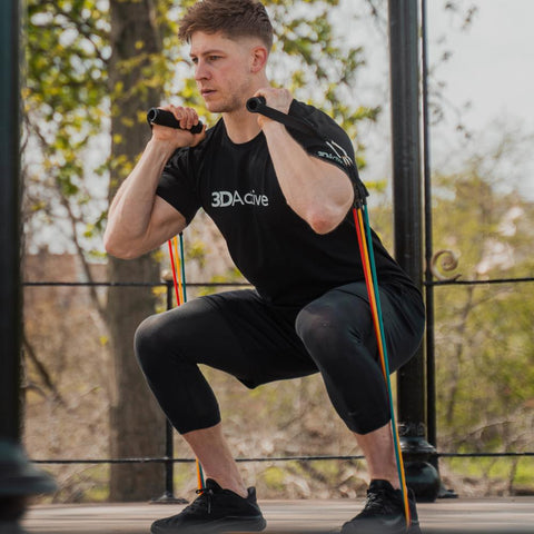 Man performing squat with 3DActive resistance bands with handles