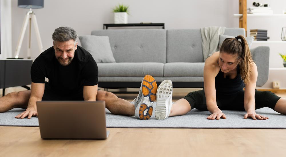 Couple stretching while looking at laptop
