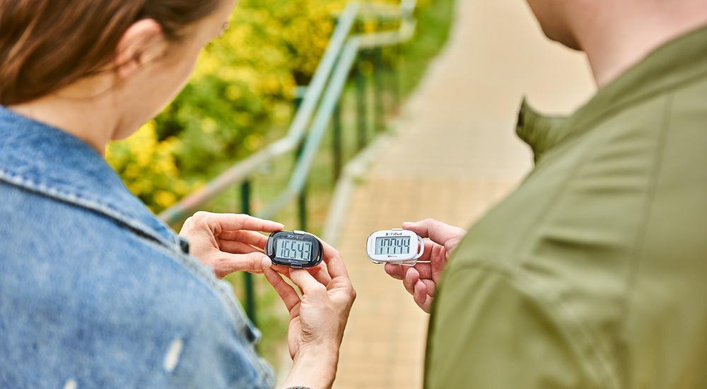 Woman and man comparing the step count on their 3DFitBud Pedometers