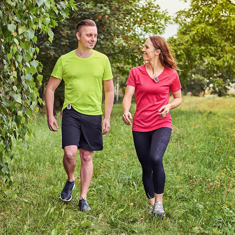 Man and woman walking outdoors wearing a 3DFitBud Pedometer clipped to their clothes