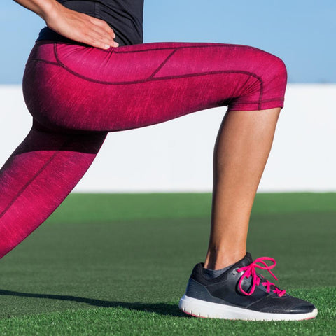 Woman in athletic clothes performing a lunge outdoors