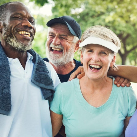 Group of three seniors in workout clothes smiling together on a walk