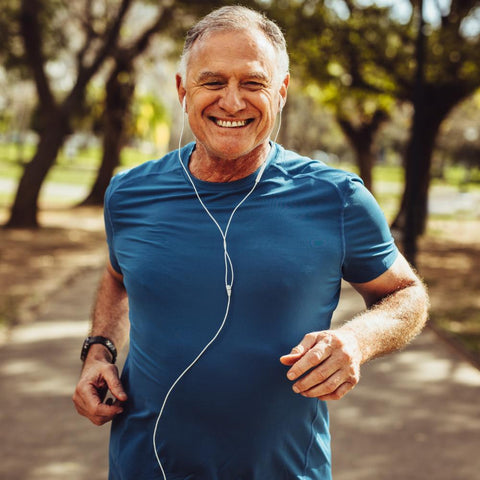 Senior man jogging outdoors while listening to music